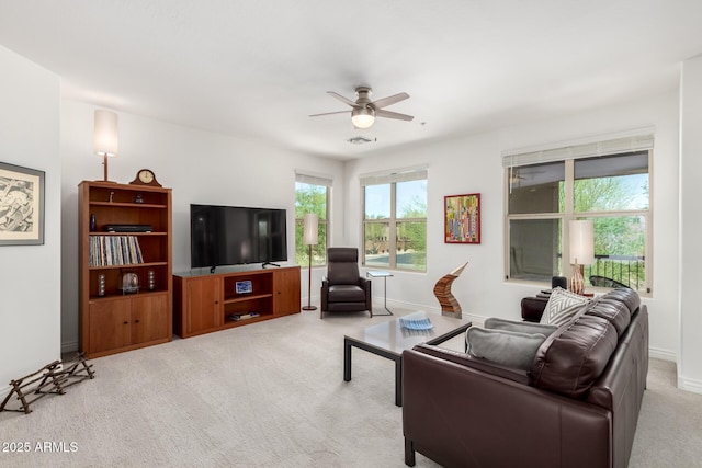 living room with light colored carpet, ceiling fan, and baseboards