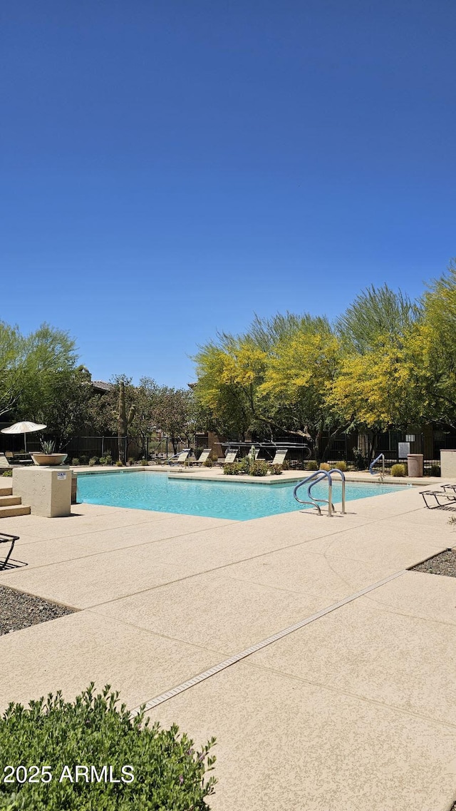 community pool with a patio and fence