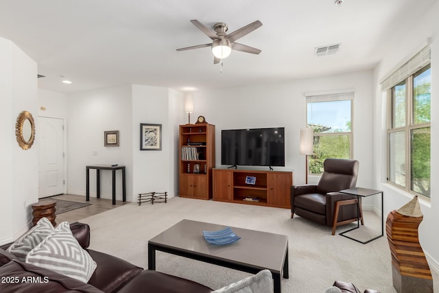 living room with a ceiling fan, light colored carpet, and baseboards
