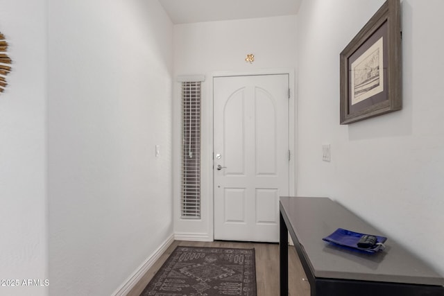 doorway to outside with light wood finished floors and baseboards