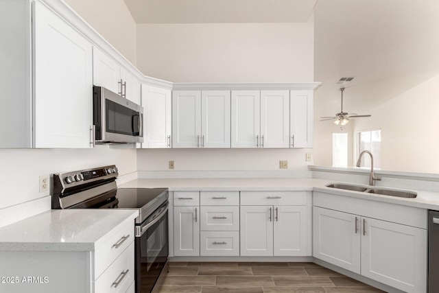 kitchen featuring appliances with stainless steel finishes, white cabinetry, sink, kitchen peninsula, and ceiling fan