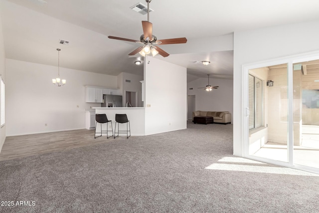 unfurnished living room with ceiling fan with notable chandelier, lofted ceiling, and carpet flooring