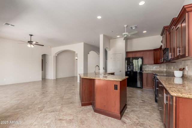 14657 N 103rd Way, Scottsdale, AZ 85255 - kitchen with black fridge with ice dispenser, a ceiling fan, arched walkways, light stone counters, and recessed lighting