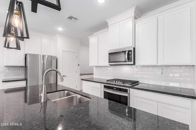 kitchen with white cabinetry, stainless steel appliances, and dark stone counters