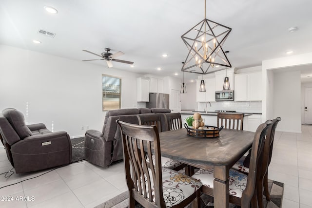 dining area with ceiling fan with notable chandelier, light tile patterned floors, and sink