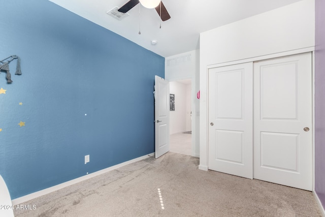 unfurnished bedroom with ceiling fan, light colored carpet, and a closet