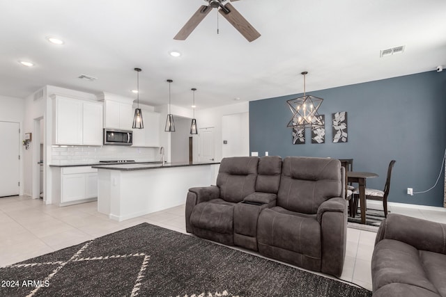 tiled living room with ceiling fan with notable chandelier and sink