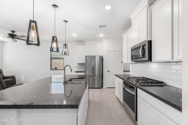 kitchen featuring sink, white cabinets, stainless steel appliances, and a center island with sink