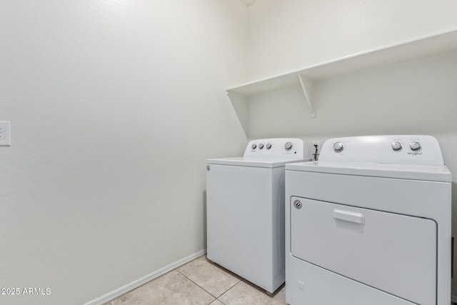 clothes washing area with laundry area, washing machine and dryer, baseboards, and light tile patterned flooring