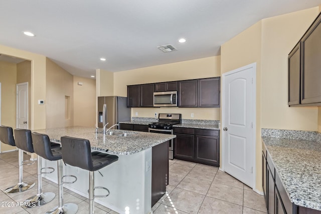 kitchen with stainless steel appliances, a breakfast bar, visible vents, and an island with sink