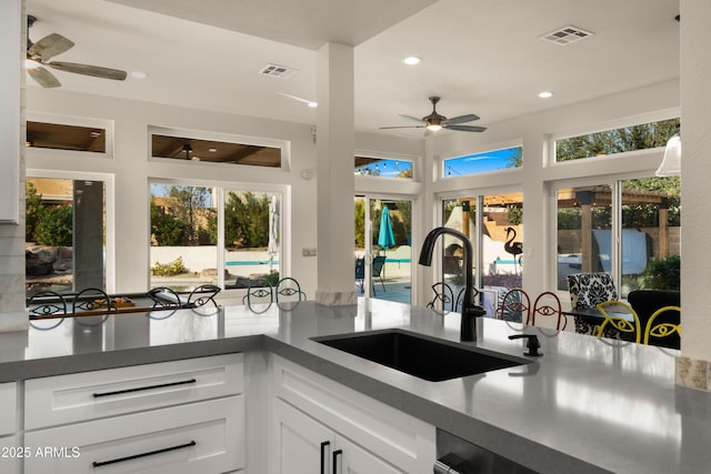 kitchen featuring visible vents, white cabinets, a sink, and recessed lighting