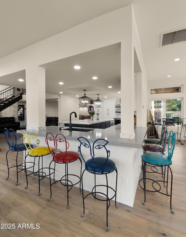 kitchen featuring a peninsula, a breakfast bar area, light wood-type flooring, and visible vents