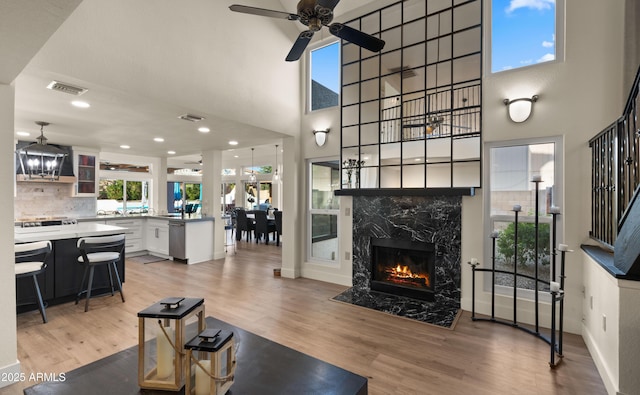 living room featuring light wood-type flooring, visible vents, baseboards, and a premium fireplace