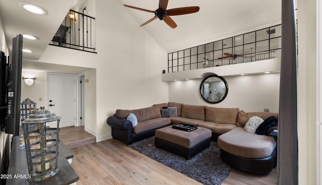 living room with high vaulted ceiling, ceiling fan, baseboards, and wood finished floors