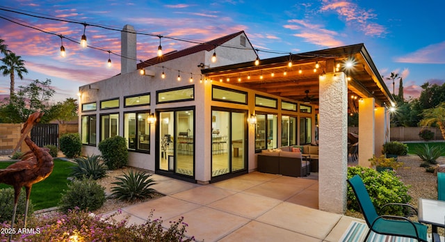 back house at dusk with a patio area and outdoor lounge area