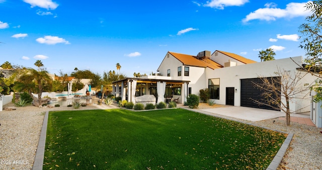 back of property featuring a garage, a patio area, a yard, and stucco siding