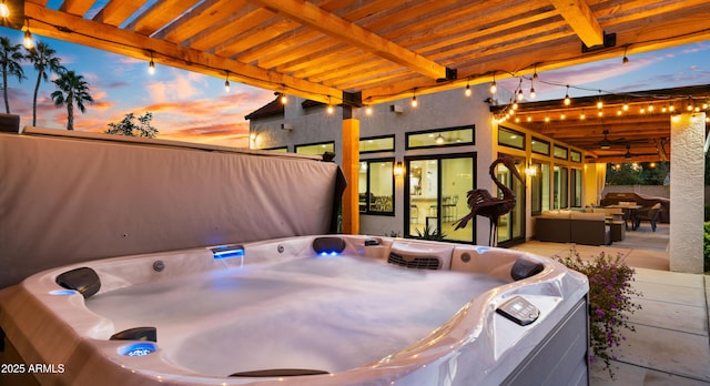 patio terrace at dusk with a ceiling fan, outdoor lounge area, and a hot tub