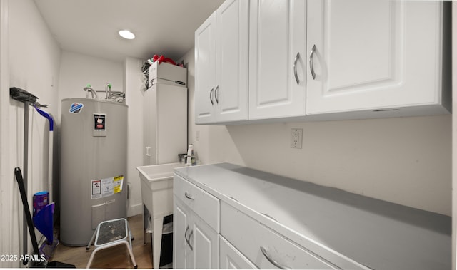 clothes washing area featuring recessed lighting, wood finished floors, and electric water heater