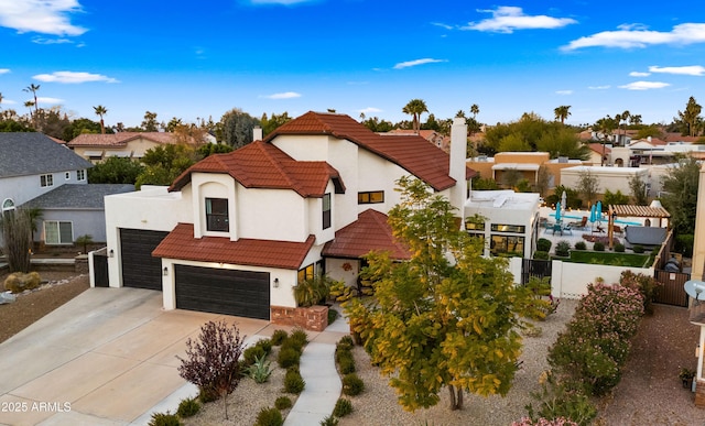 view of front facade with fence, a tiled roof, driveway, a residential view, and stucco siding