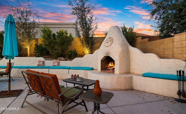 view of patio / terrace featuring a warm lit fireplace and fence