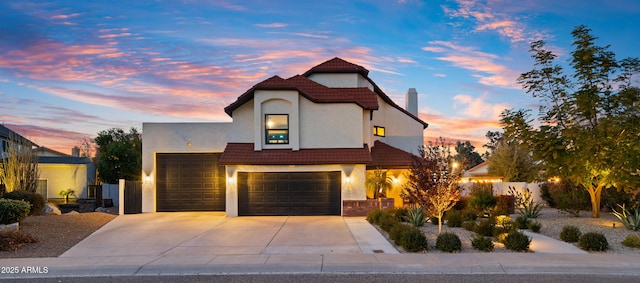 view of front of house with a tile roof, stucco siding, concrete driveway, fence, and a garage