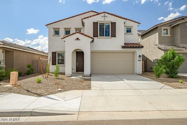 mediterranean / spanish-style house with driveway, an attached garage, a tile roof, and stucco siding