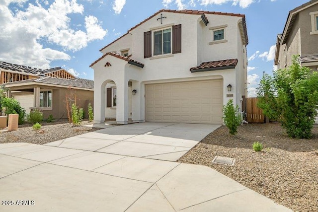 mediterranean / spanish house with concrete driveway, a tile roof, an attached garage, and stucco siding