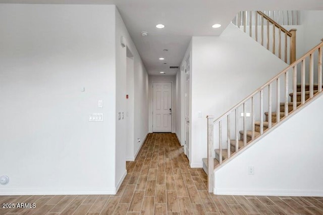 hall featuring stairs, baseboards, wood finished floors, and recessed lighting