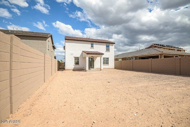 rear view of property featuring a tile roof, a fenced backyard, and stucco siding