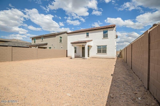 rear view of property featuring a tile roof, a fenced backyard, and stucco siding