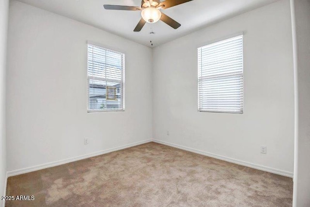 carpeted empty room with ceiling fan and baseboards