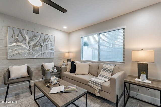 living room with brick wall, ceiling fan, a large fireplace, and light parquet floors