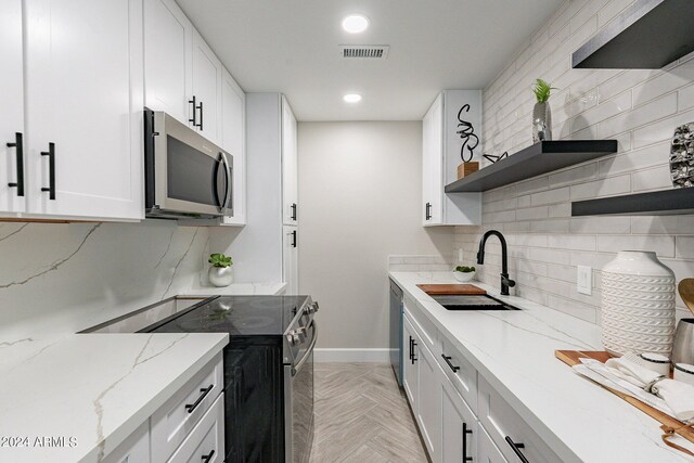 kitchen with tasteful backsplash, light parquet floors, light stone counters, and stainless steel appliances