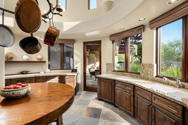 kitchen featuring plenty of natural light, sink, backsplash, and light stone counters