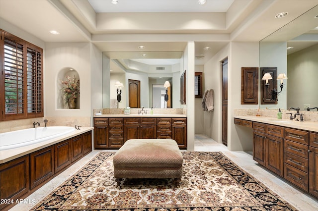 bathroom with a washtub, vanity, and a tray ceiling