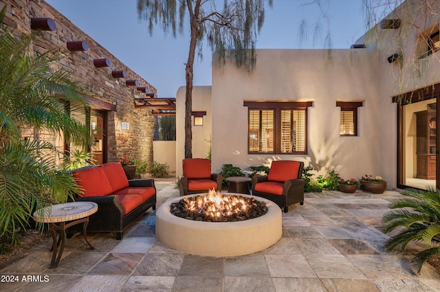 patio terrace at dusk with an outdoor living space with a fire pit