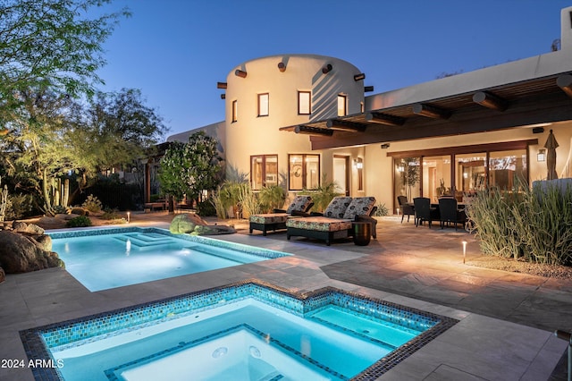 pool at dusk featuring an in ground hot tub and a patio area