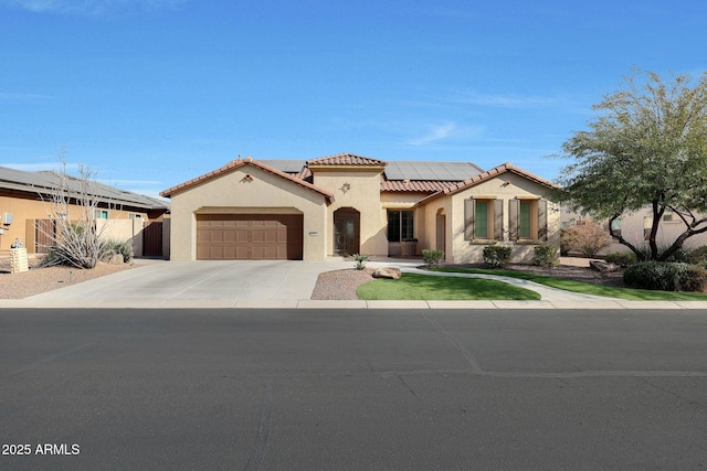 mediterranean / spanish home featuring a tile roof, concrete driveway, roof mounted solar panels, stucco siding, and an attached garage