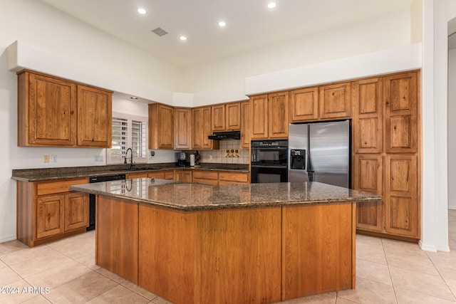 kitchen with sink, a kitchen island, black appliances, light tile patterned floors, and dark stone countertops