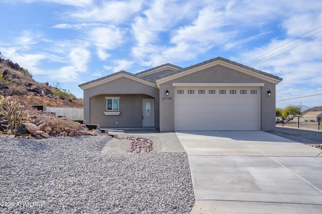 single story home with a garage, a tile roof, fence, concrete driveway, and stucco siding