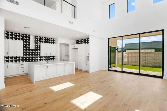 unfurnished living room with a towering ceiling and light hardwood / wood-style floors