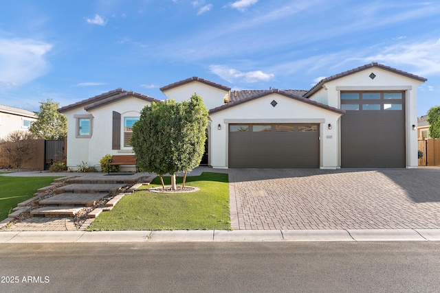 mediterranean / spanish home with an attached garage, fence, decorative driveway, and stucco siding