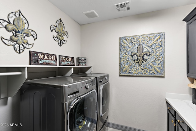 washroom featuring washer and dryer, visible vents, and cabinet space