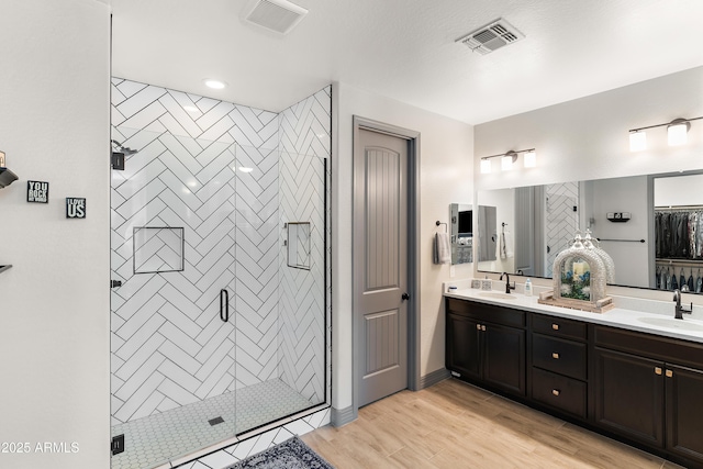 full bath featuring a shower stall, visible vents, a sink, and wood finished floors