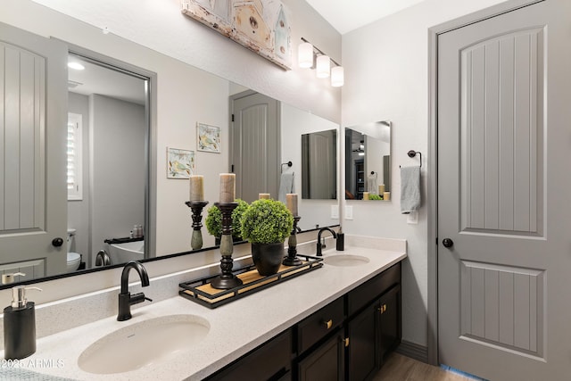 bathroom with double vanity, toilet, and a sink