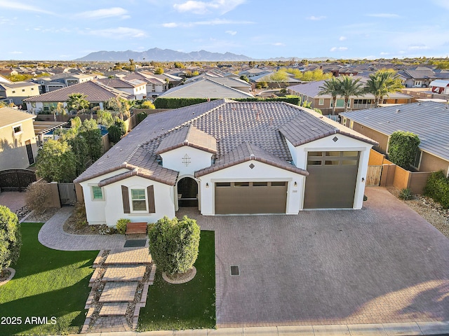 view of front of property with an attached garage, a mountain view, fence, decorative driveway, and a residential view