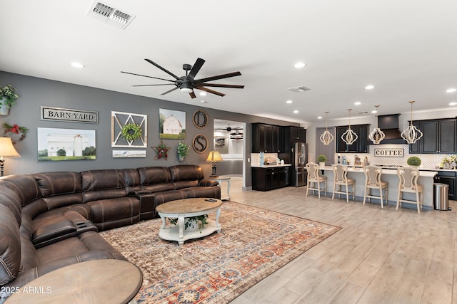 living area with light wood-style floors, ceiling fan, visible vents, and recessed lighting