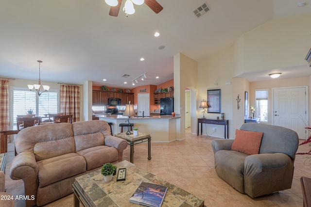 tiled living room with high vaulted ceiling, ceiling fan with notable chandelier, sink, and a wealth of natural light