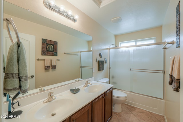 full bathroom featuring tile patterned flooring, vanity, toilet, and bath / shower combo with glass door