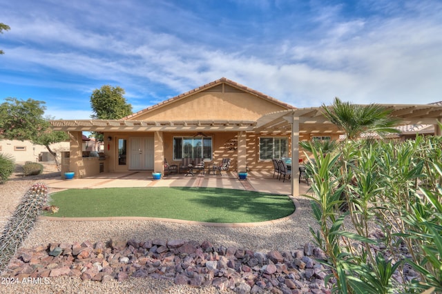 rear view of house featuring a pergola, ceiling fan, exterior kitchen, a patio area, and a yard